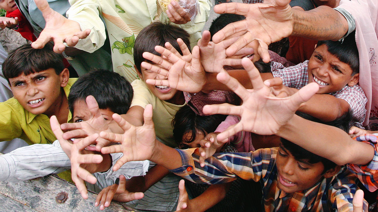 People affected by flood raise their hands toward relief supplies being distributed by the National Disaster Response Force in India
